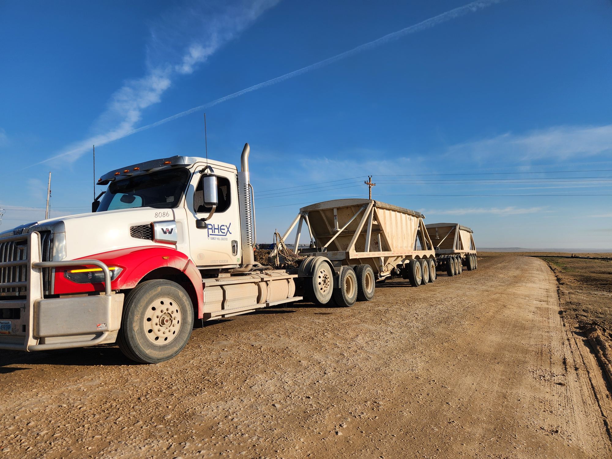 Ramsey Hill truck pulling two sand hopper trailers on a gravel road